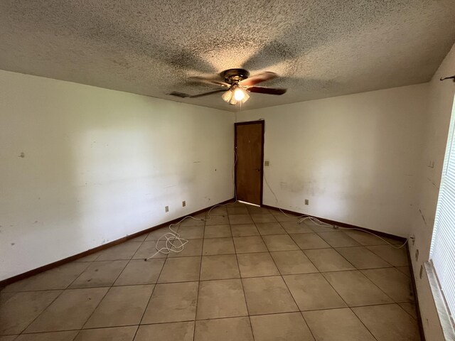 2955 SW Varsity Ln, Port Saint Lucie, FL 34953 - spare room with a ceiling fan, a textured ceiling, light tile patterned floors, and baseboards