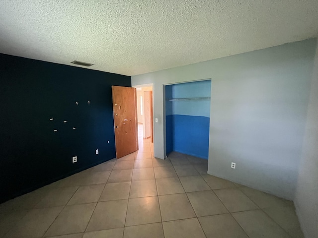 2955 SW Varsity Ln, Port Saint Lucie, FL 34953 - unfurnished bedroom featuring a textured ceiling, a closet, and light tile patterned flooring