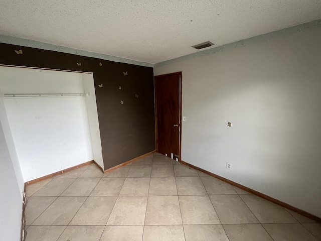2955 SW Varsity Ln, Port Saint Lucie, FL 34953 - unfurnished bedroom featuring a textured ceiling, baseboards, light tile patterned floors, and a closet
