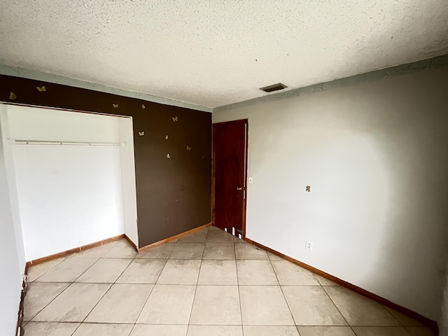 2955 SW Varsity Ln, Port Saint Lucie, FL 34953 - unfurnished bedroom with a textured ceiling, a closet, baseboards, and light tile patterned flooring
