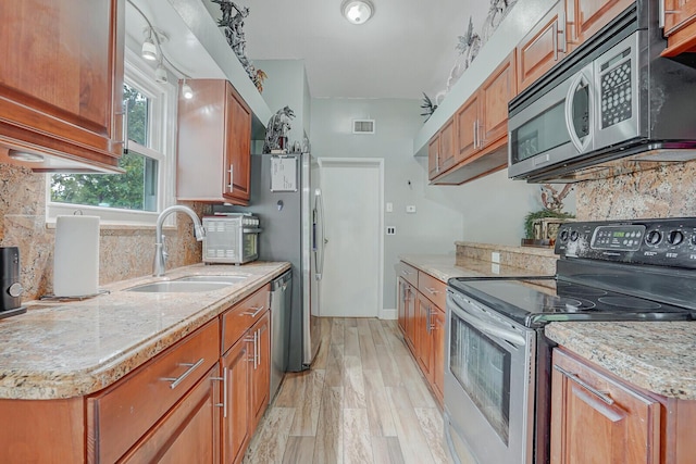 4641 Wadita Ka Way, West Palm Beach, FL 33417 - kitchen featuring appliances with stainless steel finishes, a sink, decorative backsplash, light wood-type flooring, and brown cabinetry