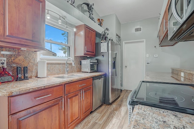 4641 Wadita Ka Way, West Palm Beach, FL 33417 - kitchen featuring appliances with stainless steel finishes, a sink, light wood finished floors, backsplash, and light stone countertops