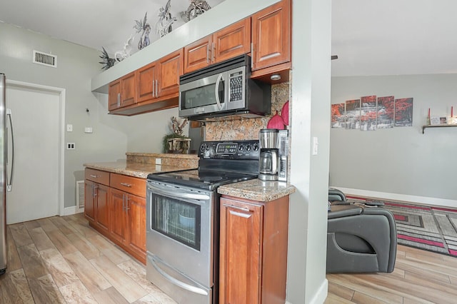 4641 Wadita Ka Way, West Palm Beach, FL 33417 - kitchen with appliances with stainless steel finishes, brown cabinetry, and light wood-style floors