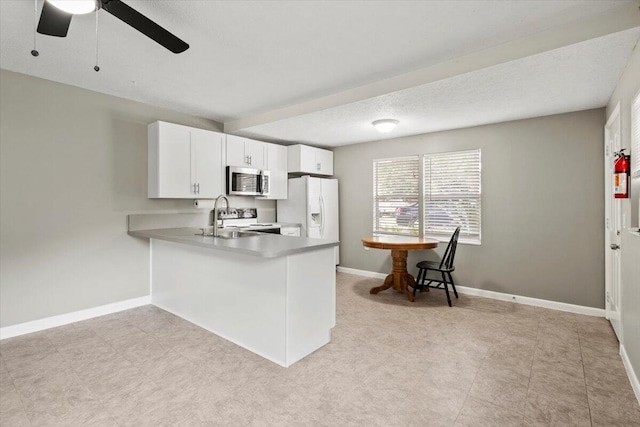 208 Olson Ave, Fort Pierce, FL 34946 - kitchen with stainless steel microwave, range, white refrigerator with ice dispenser, a peninsula, and a ceiling fan