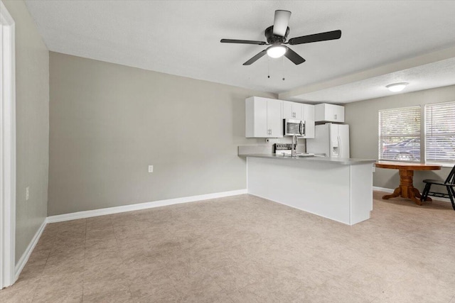 208 Olson Ave, Fort Pierce, FL 34946 - kitchen featuring white refrigerator with ice dispenser, stainless steel microwave, a peninsula, baseboards, and white cabinets