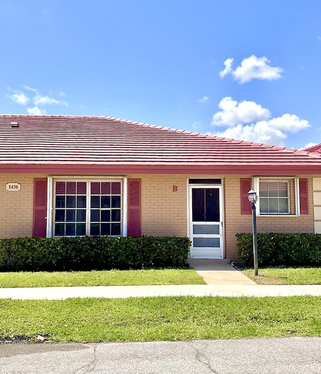 1430 SW 25th Way Unit B, Boynton Beach, FL 33426 - view of front facade with brick siding, a front lawn, and a tiled roof