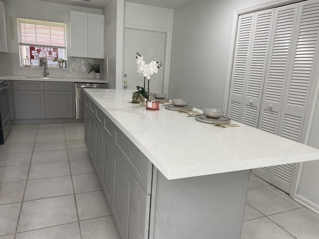 1430 SW 25th Way Unit B, Boynton Beach, FL 33426 - kitchen with gray cabinets, light tile patterned floors, stainless steel dishwasher, decorative backsplash, and a kitchen island