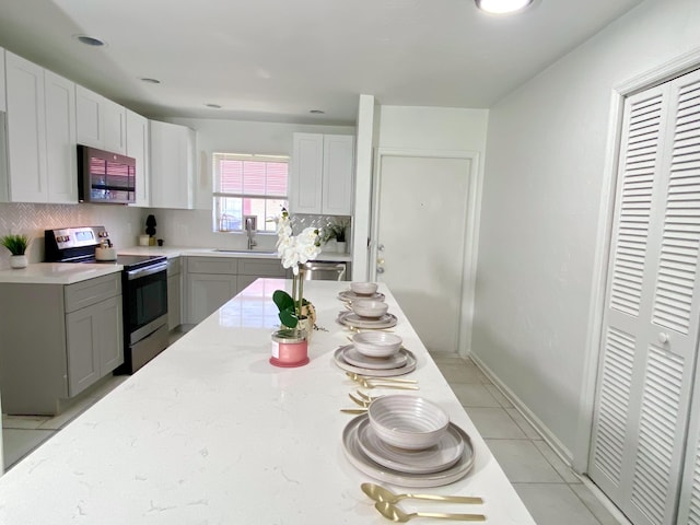 1430 SW 25th Way Unit B, Boynton Beach, FL 33426 - kitchen featuring appliances with stainless steel finishes, decorative backsplash, light stone counters, and light tile patterned floors