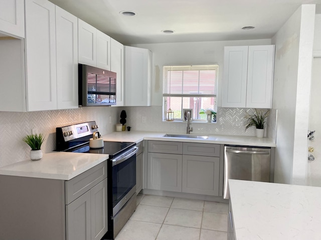 1430 SW 25th Way Unit B, Boynton Beach, FL 33426 - kitchen with appliances with stainless steel finishes, decorative backsplash, light stone counters, light tile patterned floors, and white cabinetry