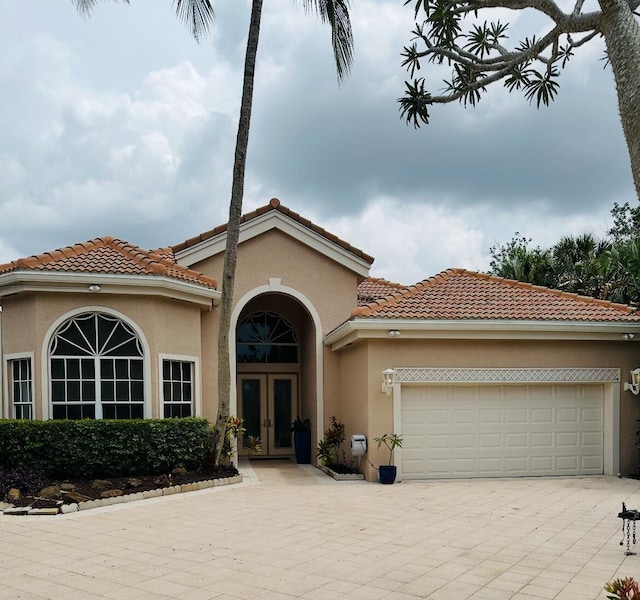 102 Windward Dr, Palm Beach Gardens, FL 33418 - mediterranean / spanish house with french doors, stucco siding, driveway, an attached garage, and a tile roof
