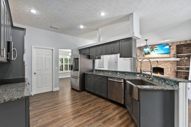 2130 W Boothe Dr, Fort Pierce, FL 34982 - kitchen with appliances with stainless steel finishes, dark wood-style flooring, a sink, a textured ceiling, and a peninsula