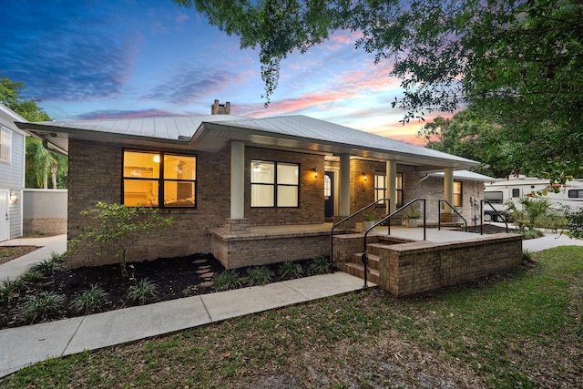 2130 W Boothe Dr, Fort Pierce, FL 34982 - ranch-style house featuring covered porch, a chimney, brick siding, metal roof, and a standing seam roof