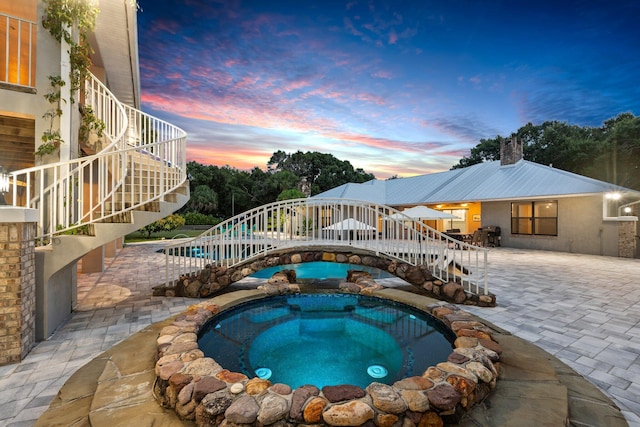 2130 W Boothe Dr, Fort Pierce, FL 34982 - pool at dusk featuring stairs, a patio area, and a pool with connected hot tub