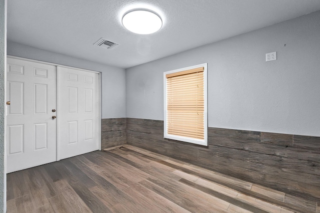 2130 W Boothe Dr, Fort Pierce, FL 34982 - unfurnished bedroom with wood finished floors, a closet, wainscoting, and a textured ceiling