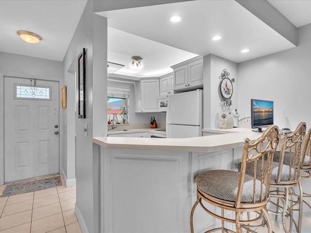 9855 Sandalfoot Blvd Unit 320, Boca Raton, FL 33428 - kitchen with freestanding refrigerator, a peninsula, light countertops, light tile patterned floors, and a breakfast bar area