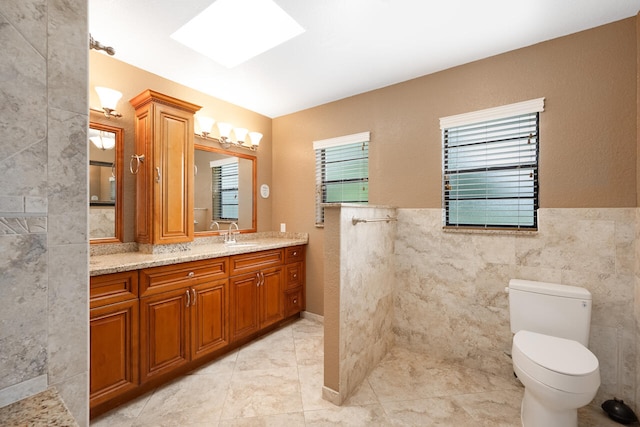 2413 NW 26th St, Boca Raton, FL 33431 - full bath featuring vanity, tile walls, toilet, a skylight, and tile patterned flooring