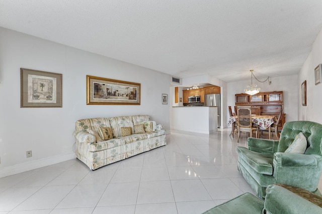 1009 N Ocean Blvd Unit 511, Pompano Beach, FL 33062 - living room featuring a chandelier, a textured ceiling, light tile patterned floors, and baseboards