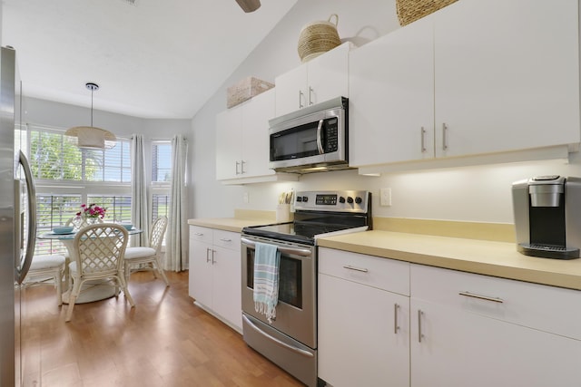 2633 SE Export Ave, Port Saint Lucie, FL 34952 - kitchen with stainless steel appliances, vaulted ceiling, light countertops, white cabinetry, and light wood-type flooring