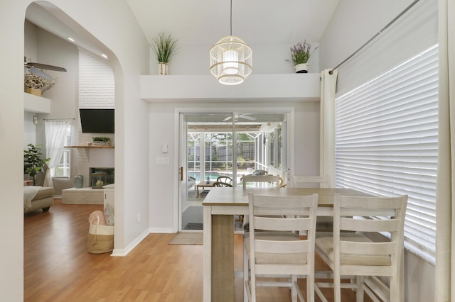 2633 SE Export Ave, Port Saint Lucie, FL 34952 - dining area featuring a ceiling fan, light wood-style floors, a brick fireplace, and a chandelier