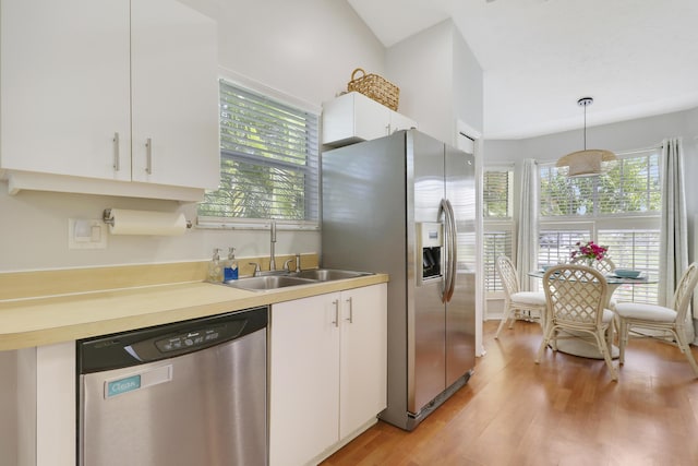 2633 SE Export Ave, Port Saint Lucie, FL 34952 - kitchen with appliances with stainless steel finishes, a sink, white cabinets, light wood finished floors, and pendant lighting