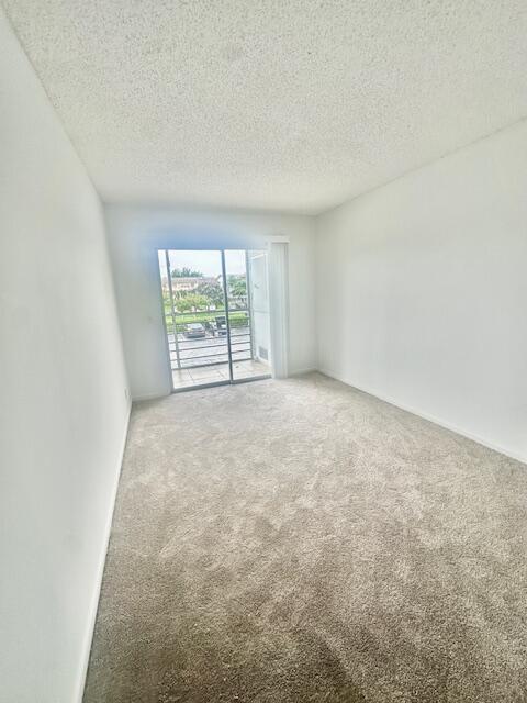 187 Preston E, Boca Raton, FL 33434 - empty room featuring carpet floors, a textured ceiling, and baseboards