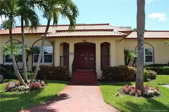 1947 SW Palm City Rd Unit G, Stuart, FL 34994 - view of front of home featuring a tile roof, stucco siding, a porch, and a front yard