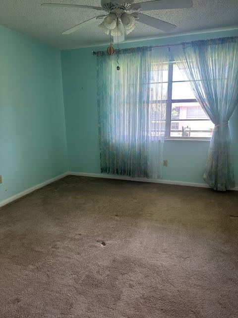 1947 SW Palm City Rd Unit G, Stuart, FL 34994 - carpeted empty room featuring a textured ceiling, a ceiling fan, and baseboards