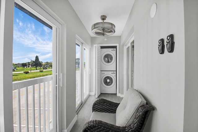 388 Tuscany G 388, Delray Beach, FL 33446 - washroom featuring stacked washer / dryer, wood finished floors, and baseboards