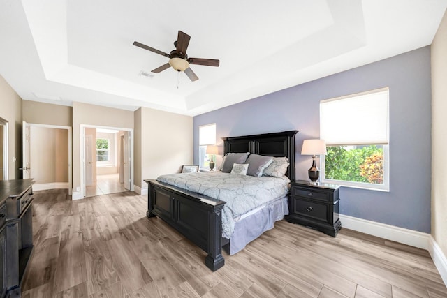 21480 Halstead Dr, Boca Raton, FL 33428 - bedroom featuring a tray ceiling, light wood finished floors, ensuite bath, and a ceiling fan