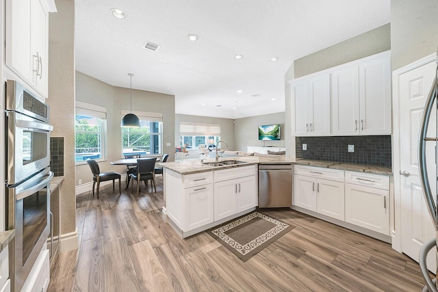 21480 Halstead Dr, Boca Raton, FL 33428 - kitchen featuring appliances with stainless steel finishes, a peninsula, white cabinets, light wood finished floors, and recessed lighting