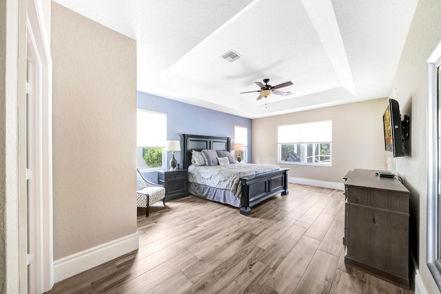 21480 Halstead Dr, Boca Raton, FL 33428 - bedroom featuring a tray ceiling, multiple windows, wood finished floors, ceiling fan, and a textured wall