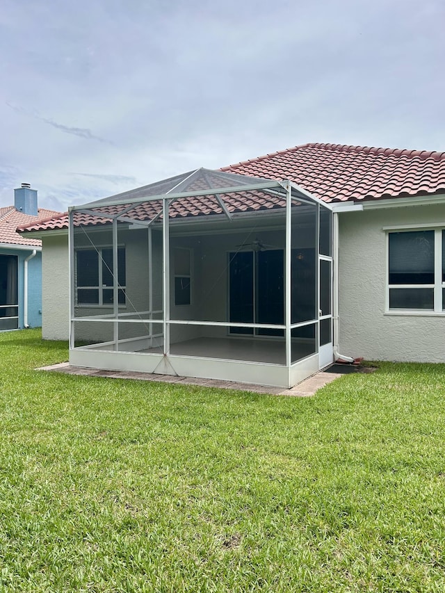 644 NW San Candido Way, Port Saint Lucie, FL 34986 - back of property featuring a tile roof, a yard, stucco siding, and glass enclosure