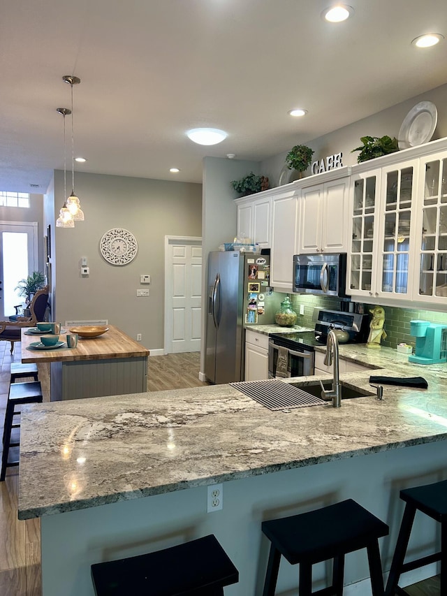 644 NW San Candido Way, Port Saint Lucie, FL 34986 - kitchen with stainless steel appliances, a kitchen breakfast bar, tasteful backsplash, white cabinetry, and recessed lighting