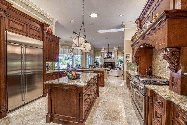 7656 Steeplechase Dr, Palm Beach Gardens, FL 33418 - kitchen featuring premium appliances, a fireplace, a peninsula, backsplash, and crown molding