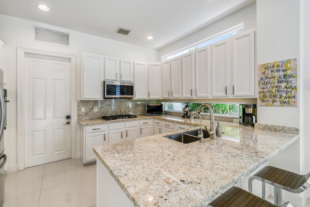 1522 Carafe Ct, Palm Beach Gardens, FL 33410 - kitchen with stainless steel microwave, a sink, a peninsula, gas cooktop, and a breakfast bar area