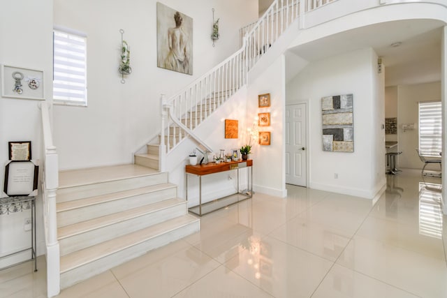1522 Carafe Ct, Palm Beach Gardens, FL 33410 - staircase with healthy amount of natural light, tile patterned flooring, arched walkways, and baseboards