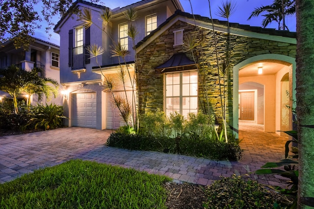 1522 Carafe Ct, Palm Beach Gardens, FL 33410 - mediterranean / spanish-style house with stone siding, stucco siding, decorative driveway, an attached garage, and a balcony
