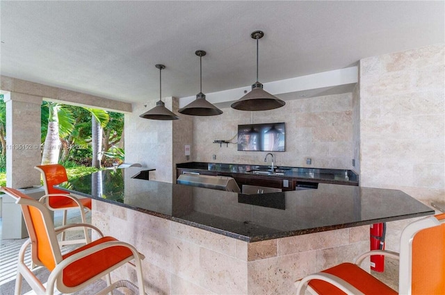 550 Okeechobee Blvd Unit Uph-15, West Palm Beach, FL 33401 - kitchen featuring a sink, dark stone counters, a breakfast bar area, and hanging light fixtures