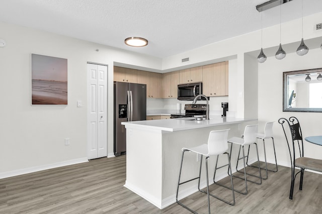 1801 N Flagler Dr Unit 622, West Palm Beach, FL 33407 - kitchen with stainless steel appliances, a breakfast bar, a peninsula, light wood-style flooring, and a textured ceiling