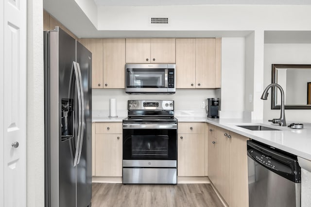 1801 N Flagler Dr Unit 622, West Palm Beach, FL 33407 - kitchen featuring appliances with stainless steel finishes, light brown cabinets, a sink, and light wood-style flooring
