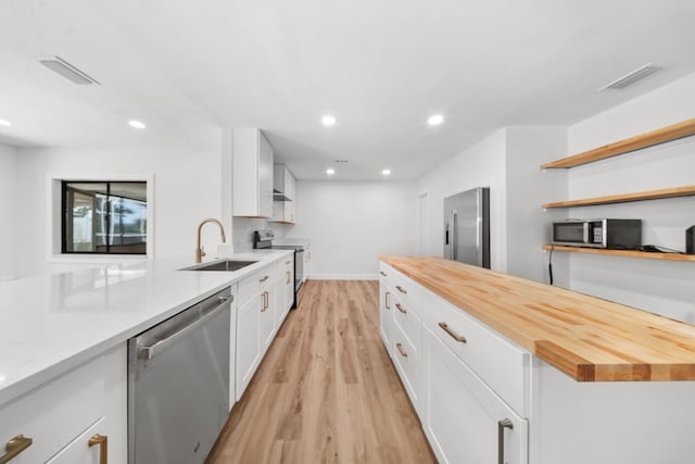 948 Canal Cir, Sebastian, FL 32958 - kitchen featuring appliances with stainless steel finishes, light wood finished floors, white cabinetry, open shelves, and butcher block counters