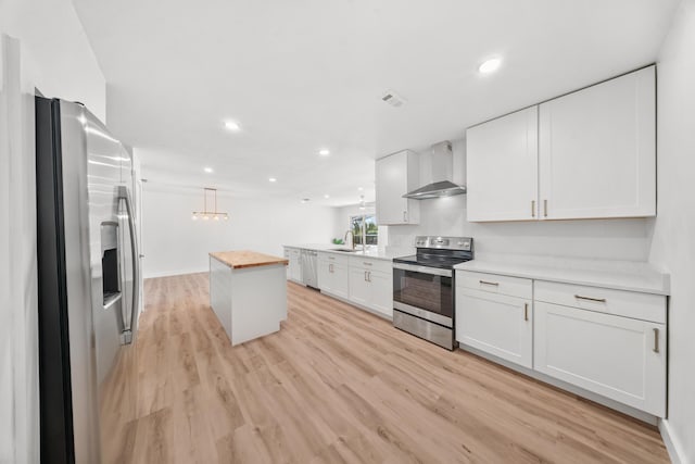 948 Canal Cir, Sebastian, FL 32958 - kitchen with stainless steel appliances, wall chimney range hood, light wood-type flooring, white cabinets, and recessed lighting