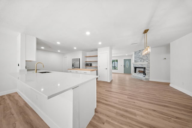 948 Canal Cir, Sebastian, FL 32958 - kitchen with white cabinetry, open shelves, light wood finished floors, a multi sided fireplace, and a peninsula