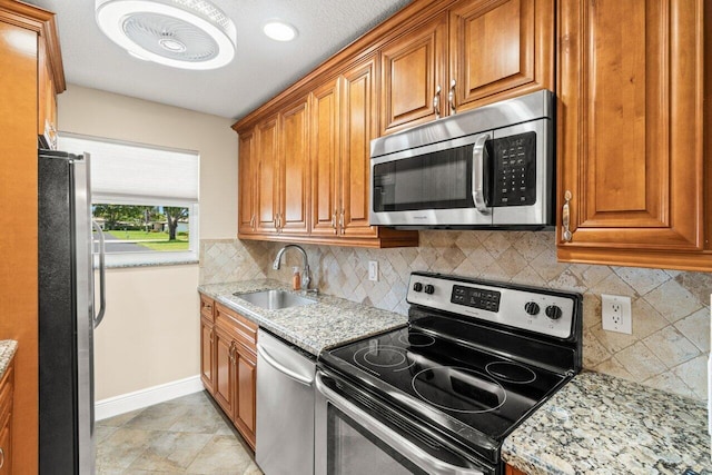 1012 Circle Ter E Unit A, Delray Beach, FL 33445 - kitchen featuring appliances with stainless steel finishes, a sink, brown cabinetry, baseboards, and decorative backsplash