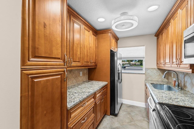 1012 Circle Ter E Unit A, Delray Beach, FL 33445 - kitchen featuring appliances with stainless steel finishes, a sink, tasteful backsplash, brown cabinets, and light stone countertops