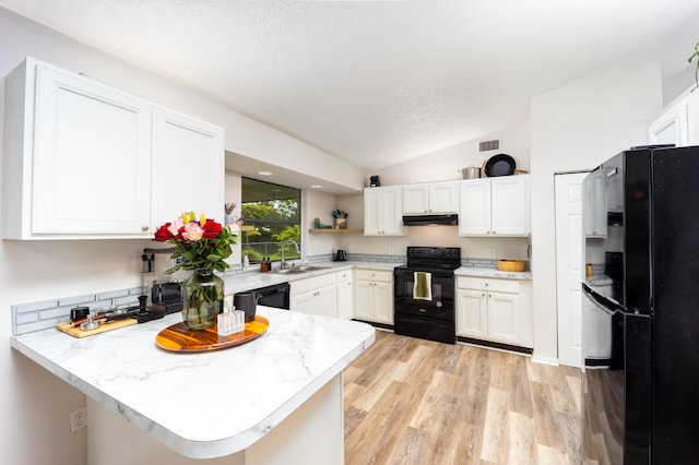 782 NW Kilpatrick Ave, Port Saint Lucie, FL 34983 - kitchen featuring black appliances, under cabinet range hood, vaulted ceiling, a peninsula, and white cabinetry