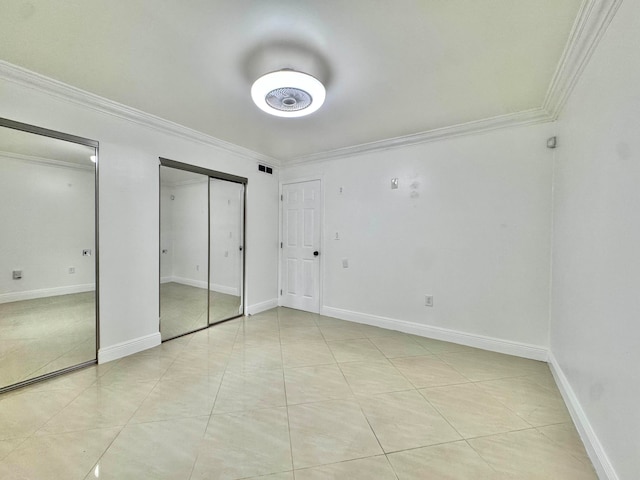 6074 Forest Hill Blvd Unit 107, West Palm Beach, FL 33415 - unfurnished bedroom featuring ornamental molding, light tile patterned flooring, two closets, and baseboards