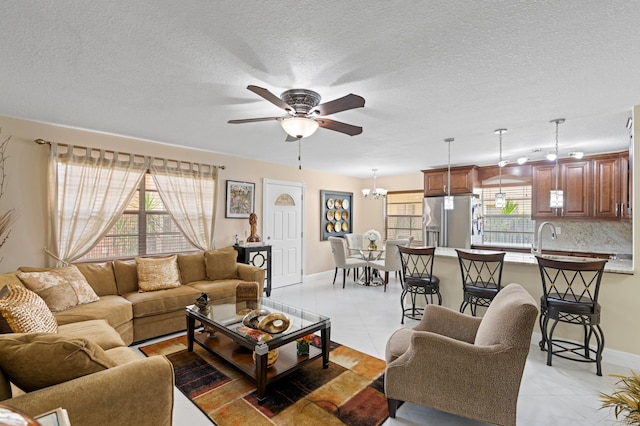 213 Piedmont E, Delray Beach, FL 33484 - living area featuring a ceiling fan, a chandelier, baseboards, light tile patterned flooring, and a textured ceiling