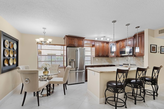 213 Piedmont E, Delray Beach, FL 33484 - kitchen featuring appliances with stainless steel finishes, a textured ceiling, light countertops, a peninsula, and decorative backsplash