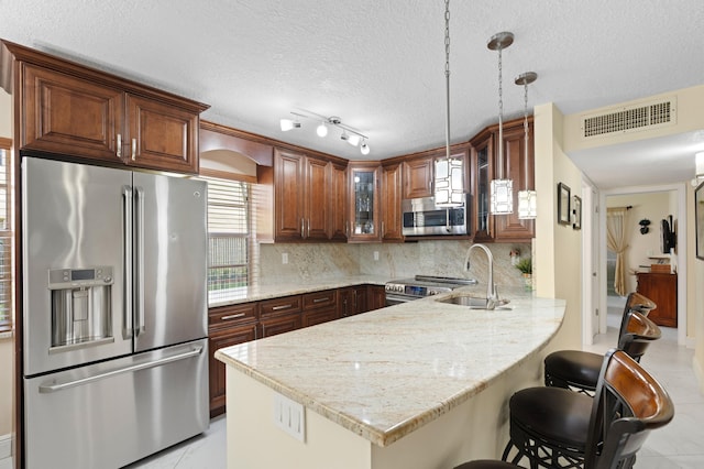 213 Piedmont E, Delray Beach, FL 33484 - kitchen featuring appliances with stainless steel finishes, a peninsula, a sink, glass insert cabinets, and a kitchen bar